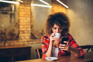 Woman in Cafe Reading on Smartphone | Global Dynamic Technology, LLC
